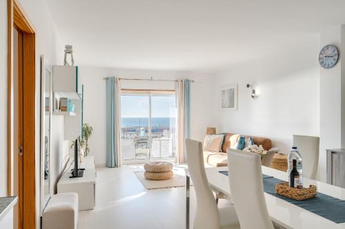 a white living room with a table and chairs at Caparica Ocean View in Costa da Caparica