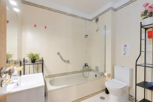 a bathroom with a tub and a toilet and a sink at Caparica Ocean View in Costa da Caparica