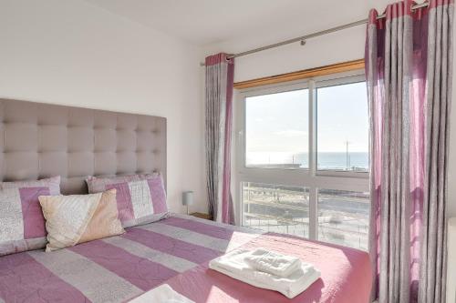 a bedroom with a bed and a large window at Caparica Ocean View in Costa da Caparica