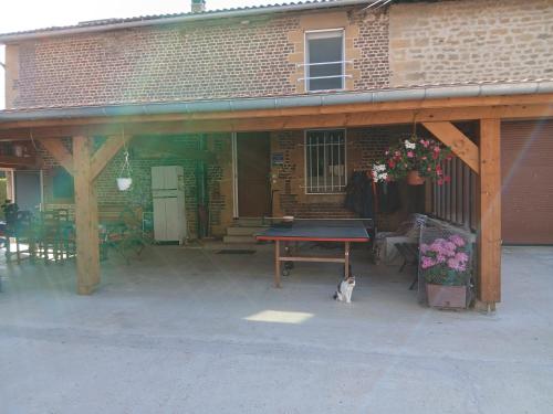 a patio with a table and a cat sitting in front of a building at CHAMBRE PRIVÉE à LA FERME in Authe