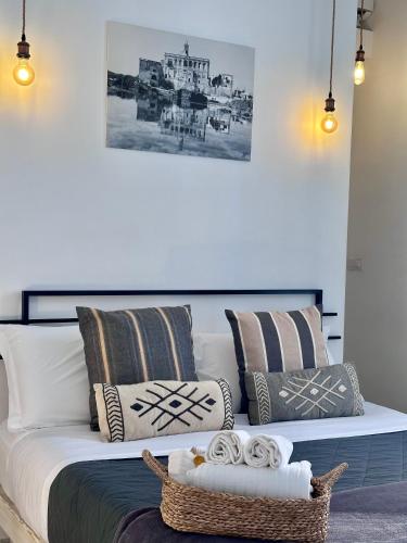 a white bed with pillows and a basket on it at Nap25guesthouse in Polignano a Mare
