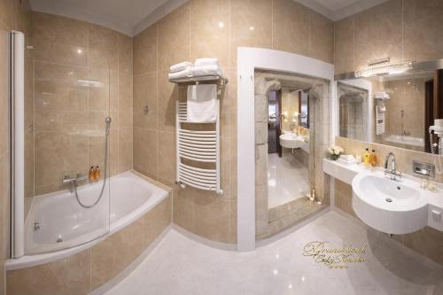 a bathroom with a tub and a sink and a shower at Hotel Grand in Český Krumlov