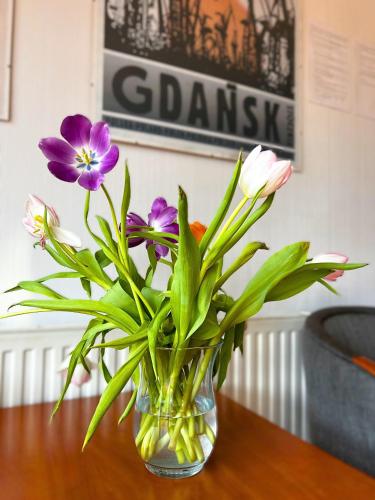 a vase filled with flowers sitting on a table at Akme APARTMENTS & ROOMS & FREE PARKING in Gdańsk