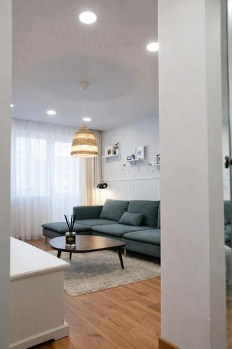 a living room with a blue couch and a coffee table at Cozy Apartment Mazeikiai in Mažeikiai