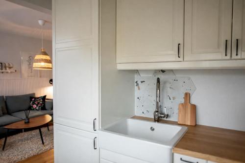 a kitchen with white cabinets and a sink at Cozy Apartment Mazeikiai in Mažeikiai