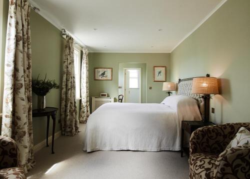 a bedroom with a white bed and a chair at The Arundell in Lifton