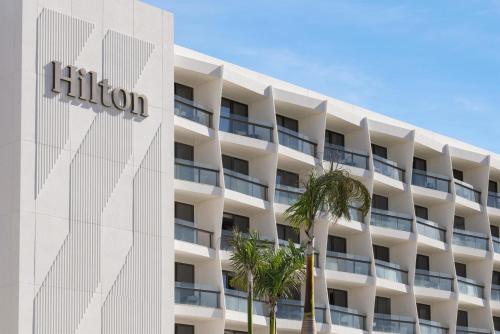 an exterior view of a hotel with palm trees at Hilton Cancun, an All-Inclusive Resort in Cancún