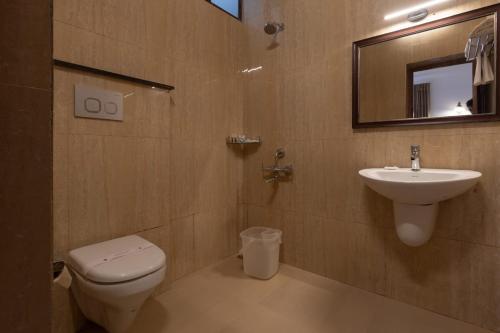 a bathroom with a sink and a toilet and a mirror at Welbeck by The Beehives in Ooty