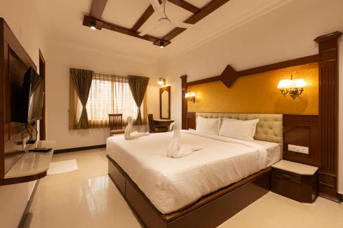 a bedroom with a large bed and a television at Welbeck by The Beehives in Ooty
