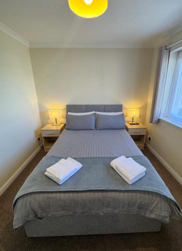 a bedroom with a bed with two towels on it at Comfortable double room with own bathroom in Inshes