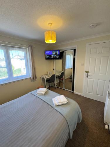 a bedroom with a bed and a desk and a television at Comfortable double room with own bathroom in Inshes