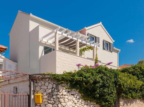 a white house on top of a stone wall at Apartment Oaza in Supetar