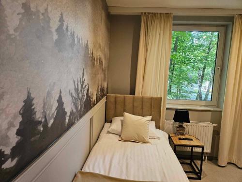 a bedroom with a bed with a large painting on the wall at Stara Palmiarnia Mimoza in Rybnik