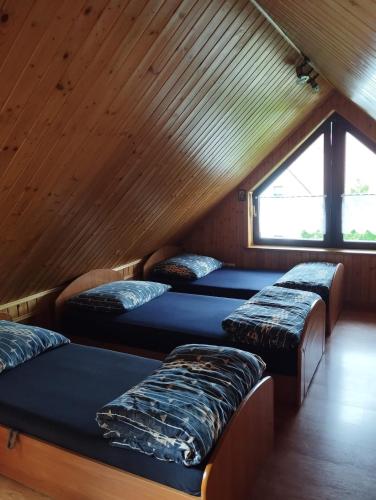 three beds in a room with a wooden ceiling at Rychwałd - Full House! in Rychwałd