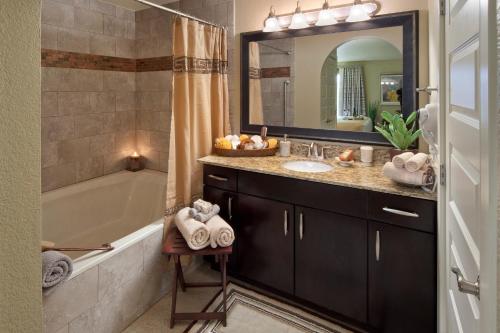a bathroom with a sink and a tub and a mirror at Holiday Inn Club Vacations at Desert Club Resort in Las Vegas