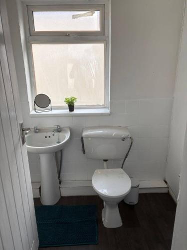 a bathroom with a toilet and a sink and a window at New Hampton Units in Wolverhampton