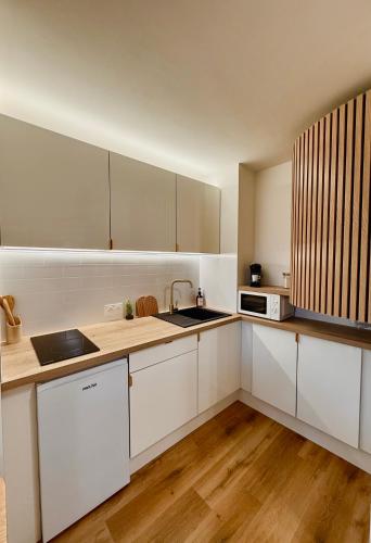 a kitchen with white cabinets and a wooden floor at FLOK horizon in Malbuisson