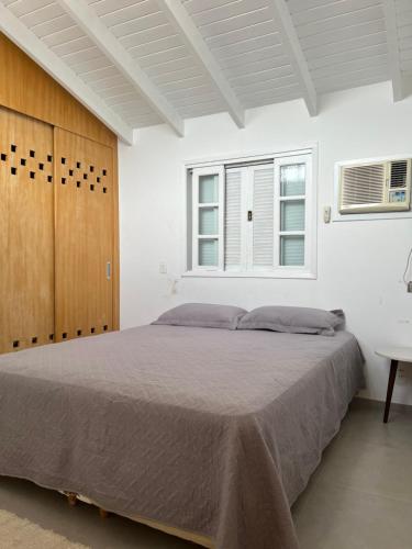 a bedroom with a large bed and a window at Flat Duplex Premium - Maresias - 150m da Praia Piscina, Wi-Fi e Garagem in São Sebastião