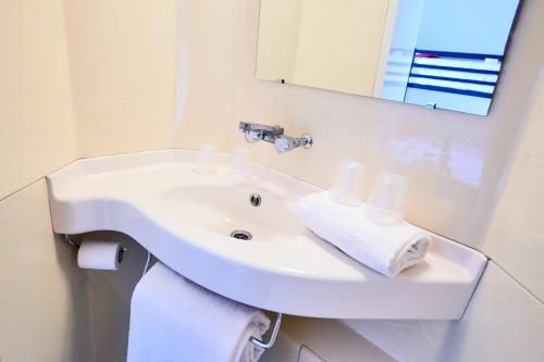 lavabo blanco en el baño con espejo en Premiere Classe Reims Sud - Bezannes en Reims
