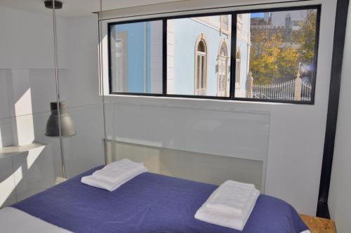 a bedroom with a blue bed and a window at Casa de São Bento by PURUS in Coimbra