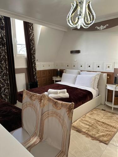a bedroom with a large bed and a chandelier at Évasion à 10 Minutes de Paris Logements Privés in Deuil-la-Barre