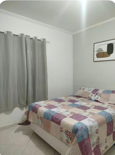 a bedroom with a bed with a quilt on it at Casa aconchego in São Carlos