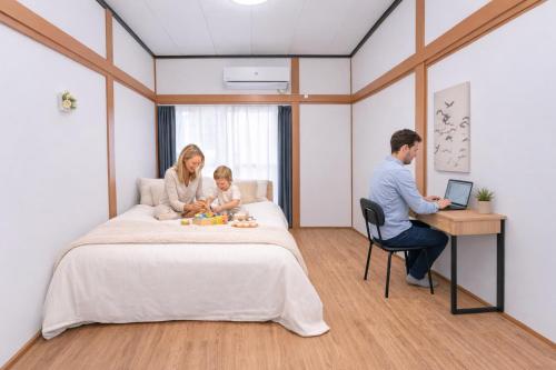 a family sitting on a bed in a hotel room at 6 minutes walk from Ichikawa Station Single-family house with 3 bedrooms and 1 living room Rich living facilities around in Ichikawa