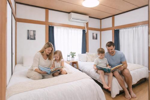 a family sitting on beds reading books in a bedroom at 6 minutes walk from Ichikawa Station Single-family house with 3 bedrooms and 1 living room Rich living facilities around in Ichikawa