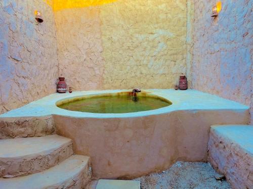 a bathroom with a bath tub with stairs in it at Adrartaziry in Siwa