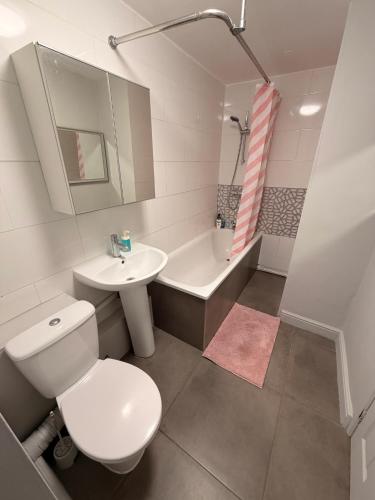 a bathroom with a toilet and a sink and a tub at Cosy Double Room in Shared Flat in Sutton