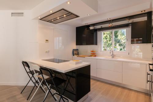a kitchen with white cabinets and a island with bar stools at Villa Blanca Santa Eulalia in Santa Eularia des Riu