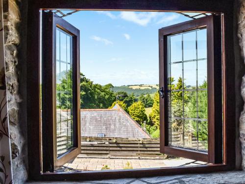 an open window with a view of a house at The Hayloft - Uk50027 in Liskeard