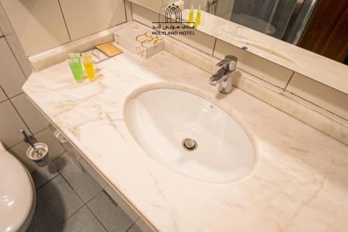 a bathroom counter with a sink and a toilet at Holyland Hotel Amman in Amman