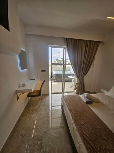 a hotel room with a bed and a desk and a window at Casa Blue Sarantis in Faliraki