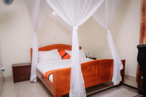 a bedroom with a canopy bed with white drapes at Kampala Kolping Hotel in Kampala