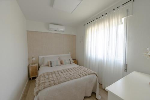 a white bedroom with a bed and a window at Casa Estação Douro Vista in Vila Marim