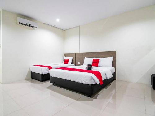 a bedroom with two beds with red and white pillows at RedDoorz @ Baloi Batam in Batam Center