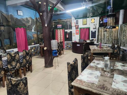 a room with tables and chairs and a tree at Orchid Resort in Lataguri