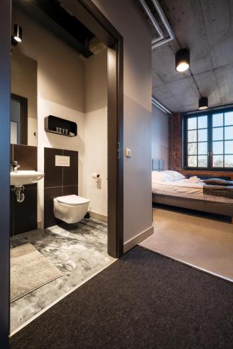 a bathroom with a sink and a toilet and a bed at ON Rooms Łódź in Łódź