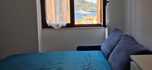 a bedroom with a blue bed and a window at La Casetta Mare in Palinuro