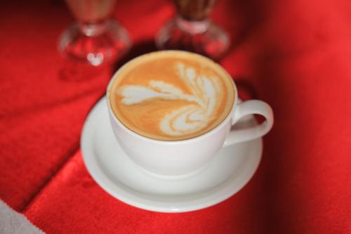 a cup of coffee sitting on a red table at HOIMA KOLPING HOTEL in Hoima
