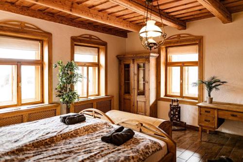 a bedroom with a bed and a desk and windows at 100éves Vendégház in Hárskút