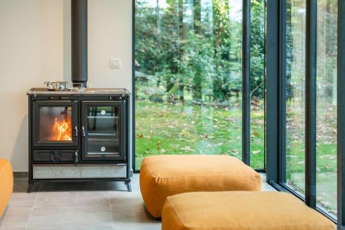 a living room with a fireplace in front of a window at Glass Forest Cabin Holenduif I Privacy I 3BR Quiet in Oostkamp