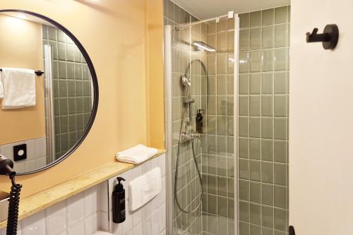 a bathroom with a glass shower with a mirror at Hotel Boulevard in Stuttgart