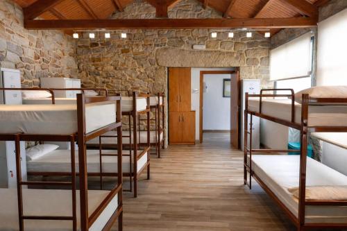 a row of bunk beds in a room with a stone wall at Miraz Albergue O Abrigo in Miraz