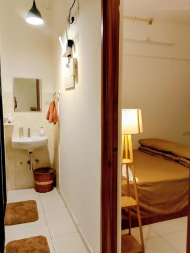 a bathroom with a sink and a mirror and a bed at MaEra's Den in Hinjewadi