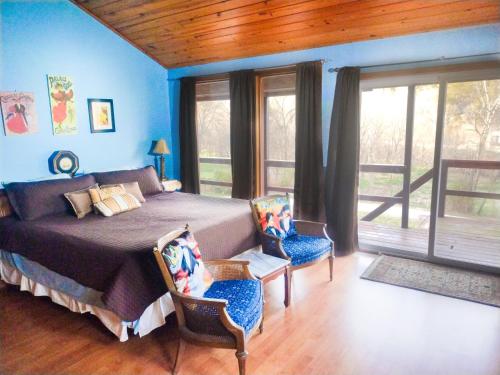a bedroom with a bed with blue walls and windows at Buffalo River Misty Creek Lodge in Vendor