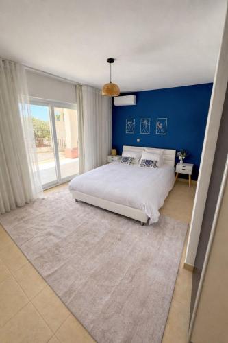 a bedroom with a large bed and a blue wall at Apartamento Paradise beach in Prainha