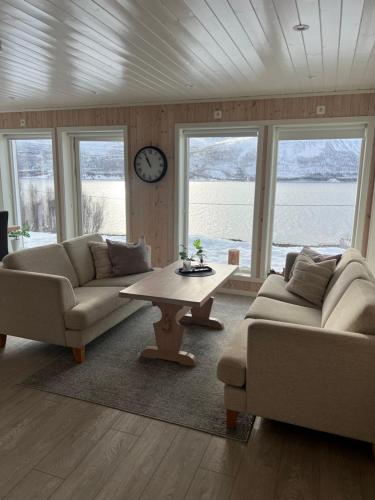 a living room with two couches and a table and a clock at Ocean View Cottage in Alta