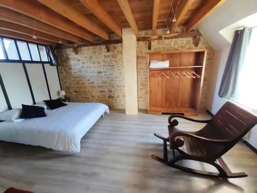 a bedroom with a bed and a chair in a room at Gîte Le Petit Menhir in Trans